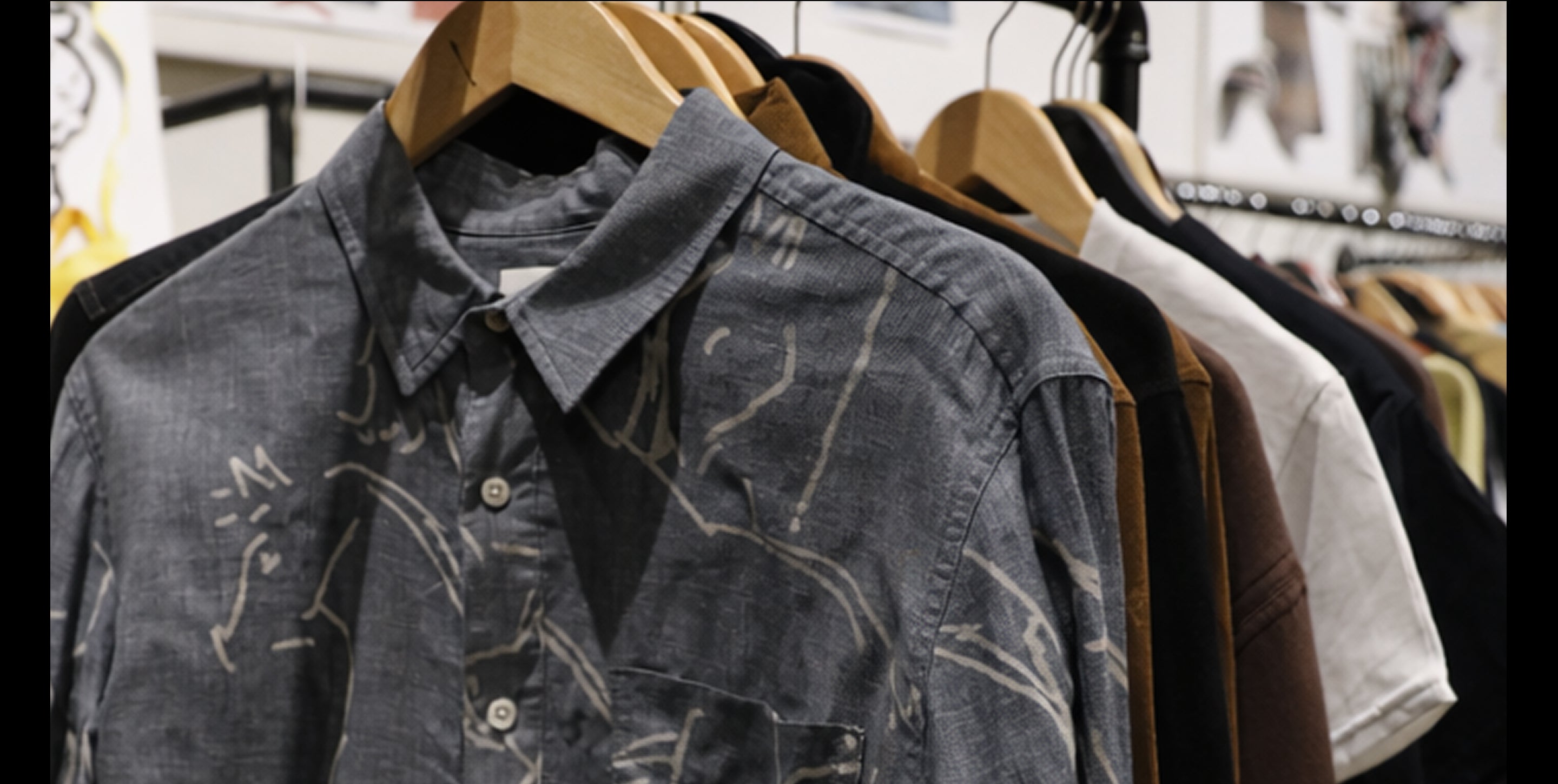 Dark gray shirt with white abstract patterns on a rack of clothes