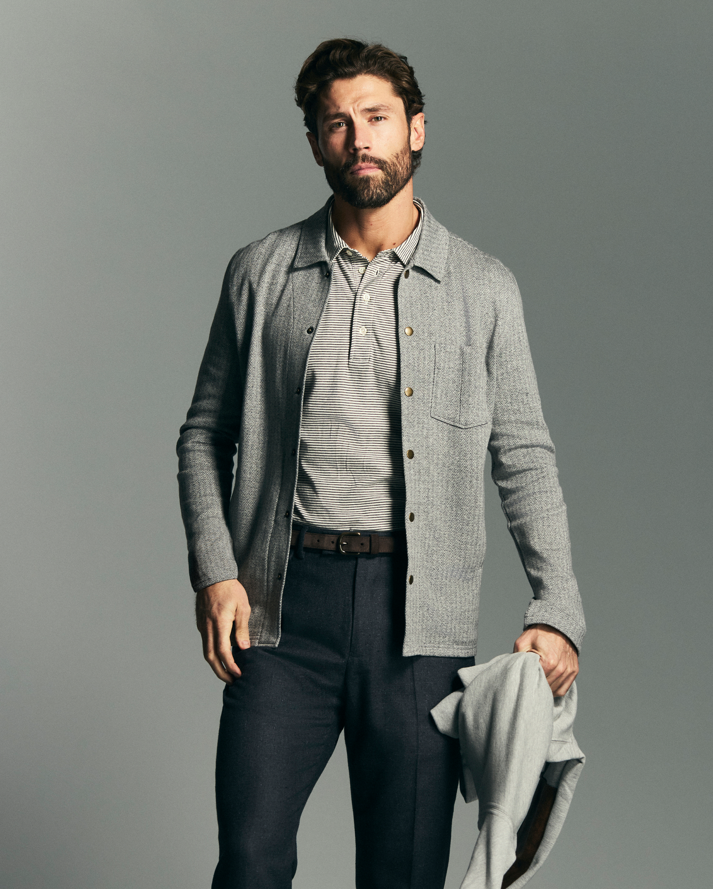Man wearing a gray jacket over a shirt with a plain background