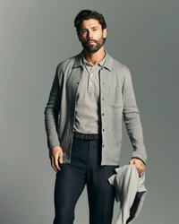 Man wearing a gray jacket over a shirt with a plain background