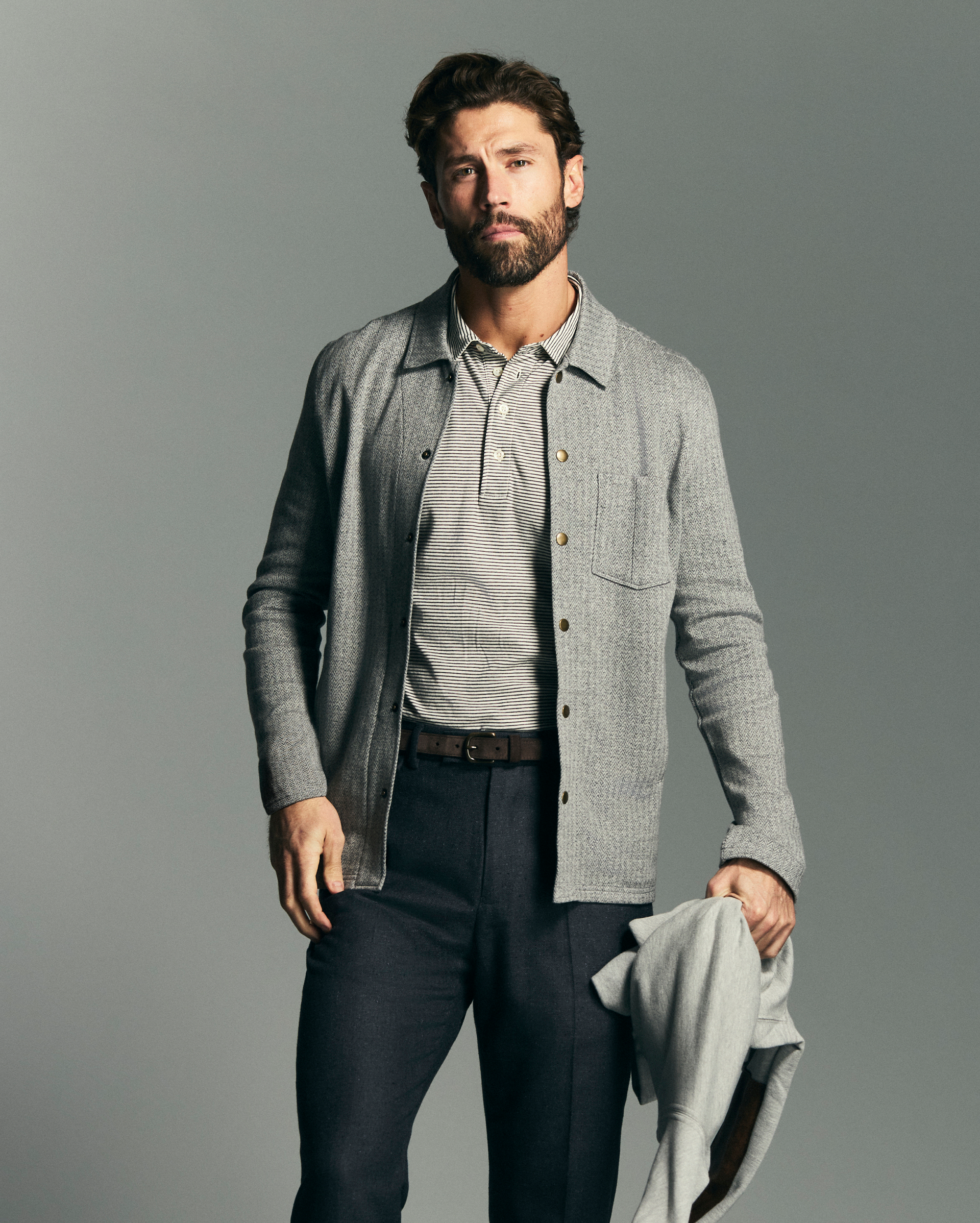 Man wearing a gray jacket over a shirt with a plain background