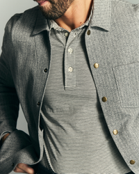 Man wearing a gray textured jacket over a striped shirt against a neutral background