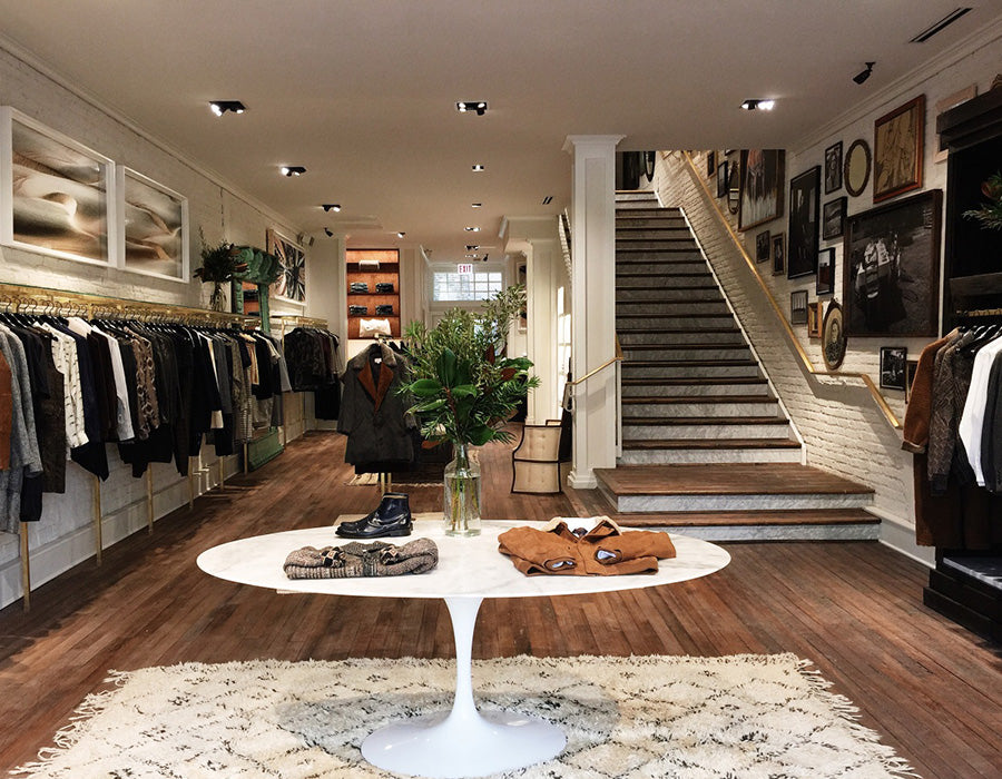 Luxury clothing store interior with staircase and display tables.