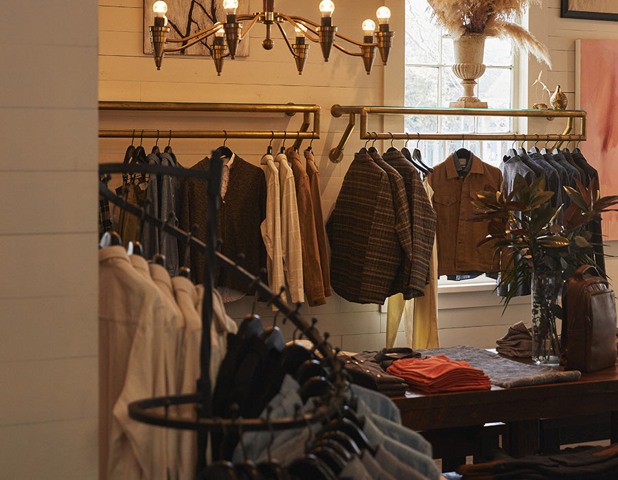 Clothing store interior with racks of clothes and a chandelier.