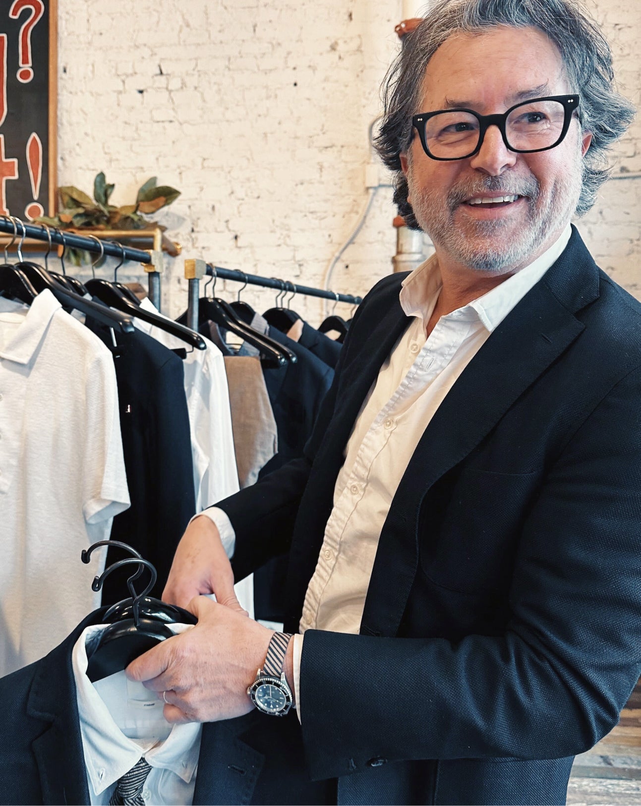 Man in a clothing store holding a jacket with clothes on racks in the background