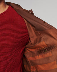Close-up of a person wearing a brown textured overshirt over a deep red waffle-knit sweater, against a light gray background.