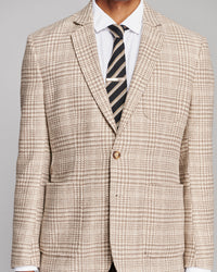 A men's single-breasted suit jacket in a beige and brown houndstooth pattern, styled with a white dress shirt and a dark striped tie, shown on a model against a neutral gray background.