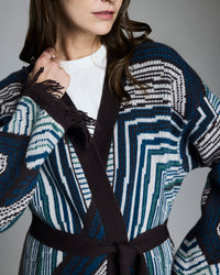 Person wearing a patterned cardigan with a gray background