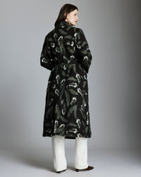 Woman wearing a black patterned coat against a gray background