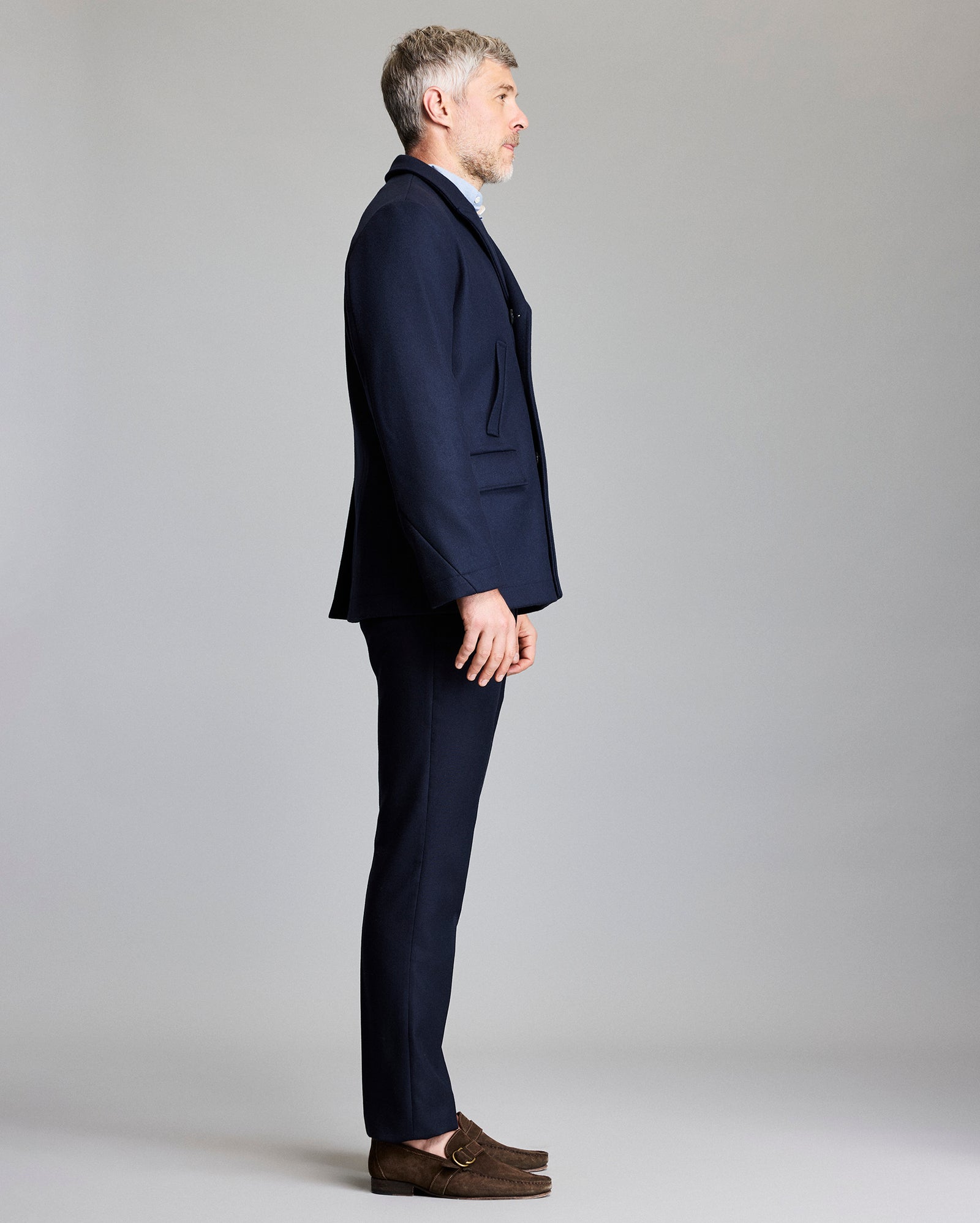 Man wearing a navy suit standing against a plain background