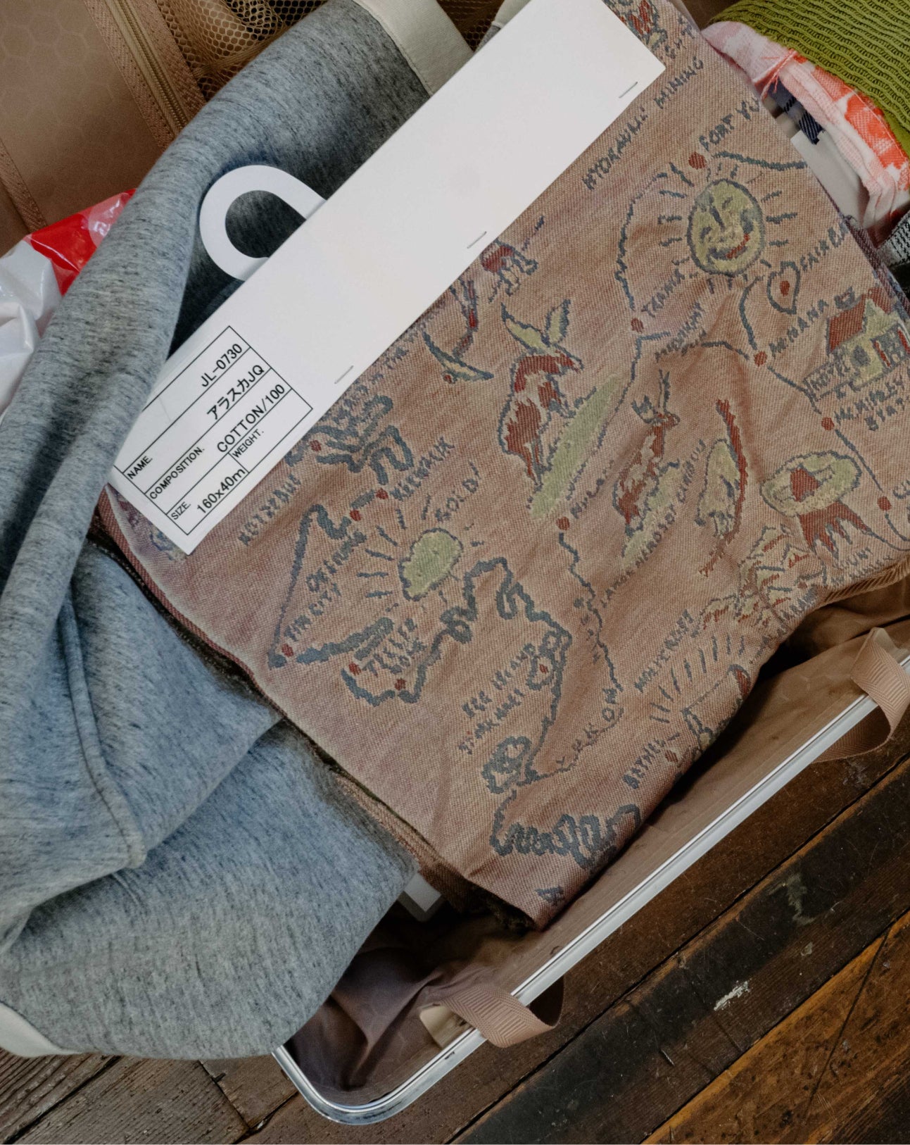 Brown fabric with drawings on a wooden surface with clothes and a box in the background