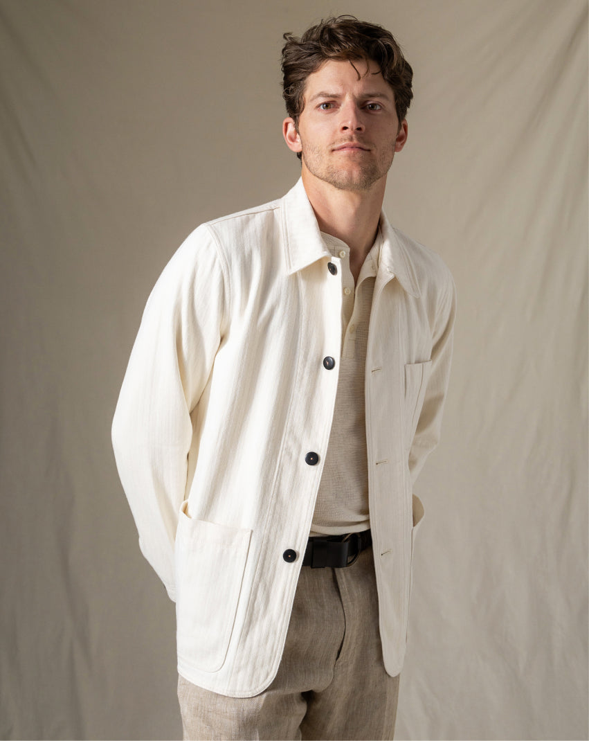 Man wearing a light-colored jacket over a shirt with a neutral background