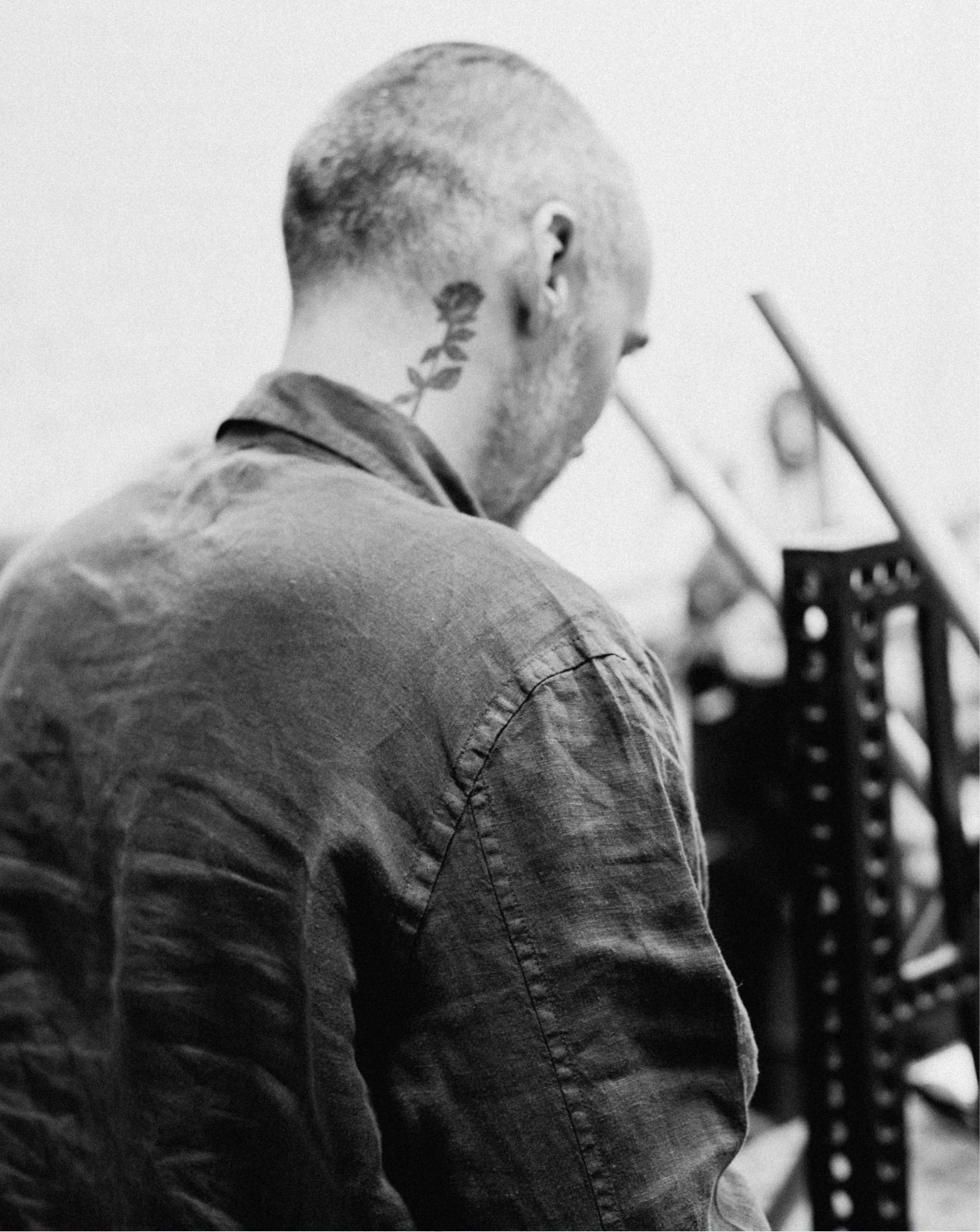 Person with a tattoo on their neck wearing a dark shirt, standing outdoors.
