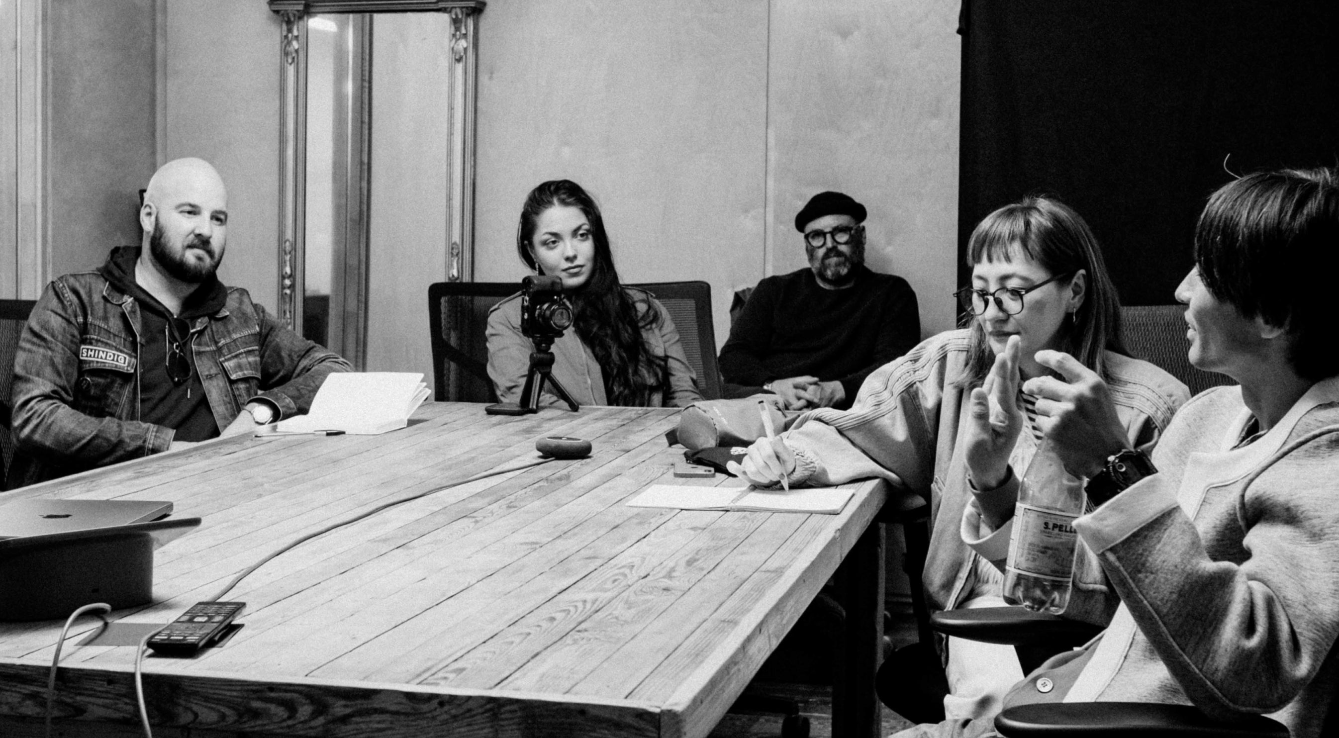 Group of people sitting around a table in a room with a neutral background
