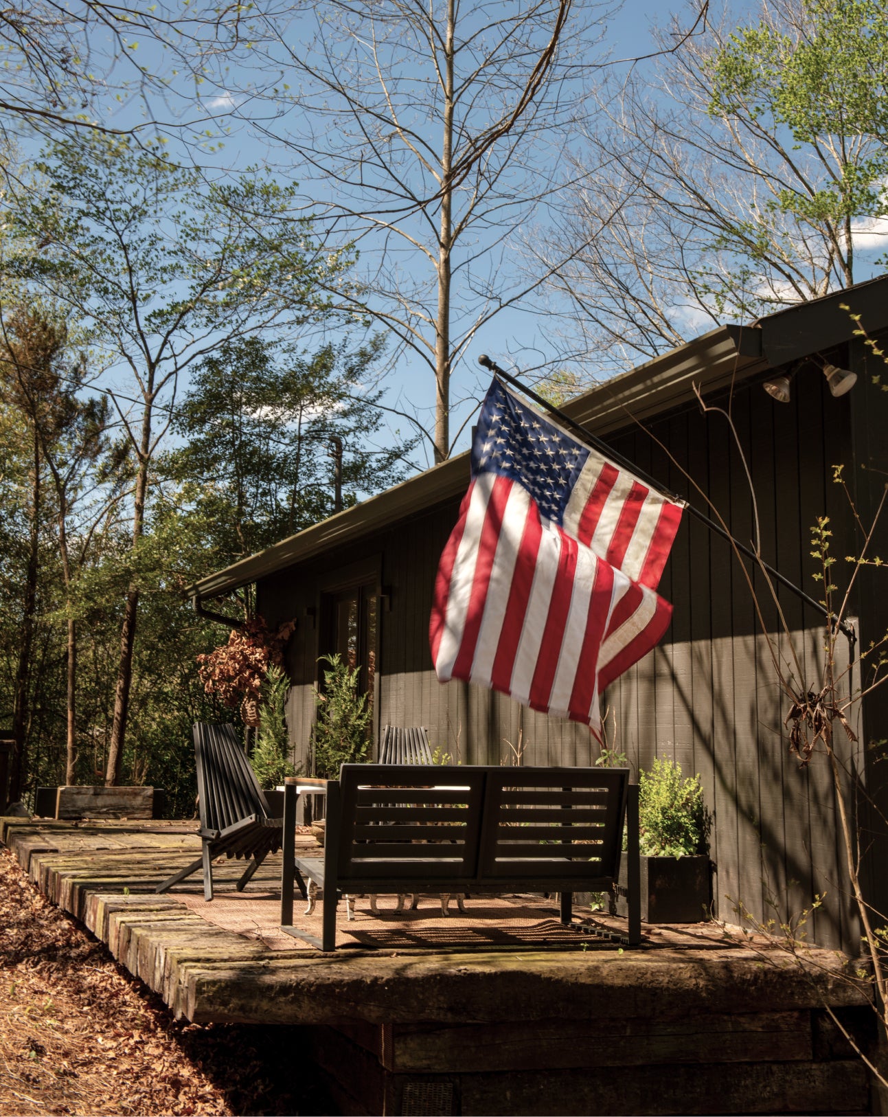 Wooden cabin with American flag on a wooden deck surrounded by trees
