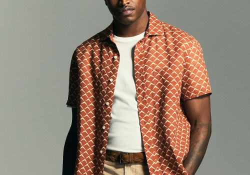 Model wears an orange shirt on a grey background.