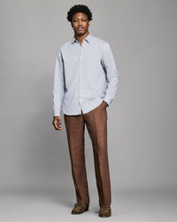 Man wearing a light gray shirt and brown pants against a plain background