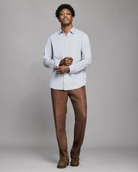 Man wearing a light gray shirt and brown pants against a plain background
