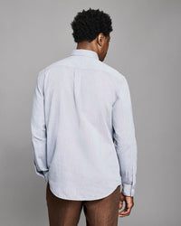 Person wearing a light blue shirt against a gray background