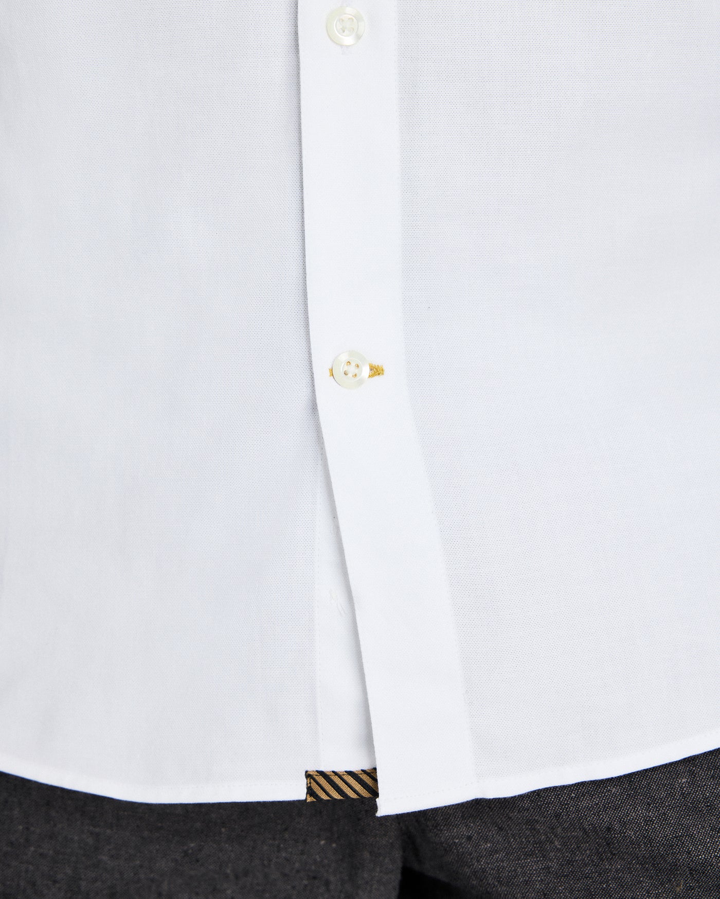 Close-up of a white shirt with a button and cuff detail on a white background