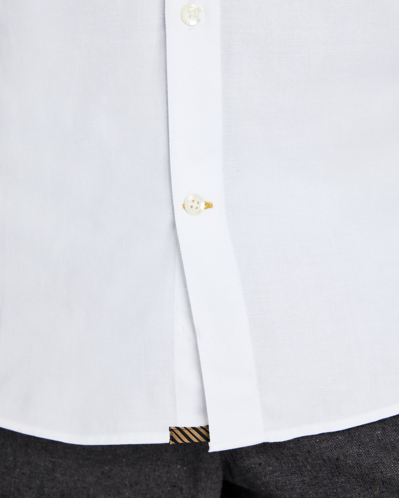 Close-up of a white shirt with a button and cuff detail on a white background