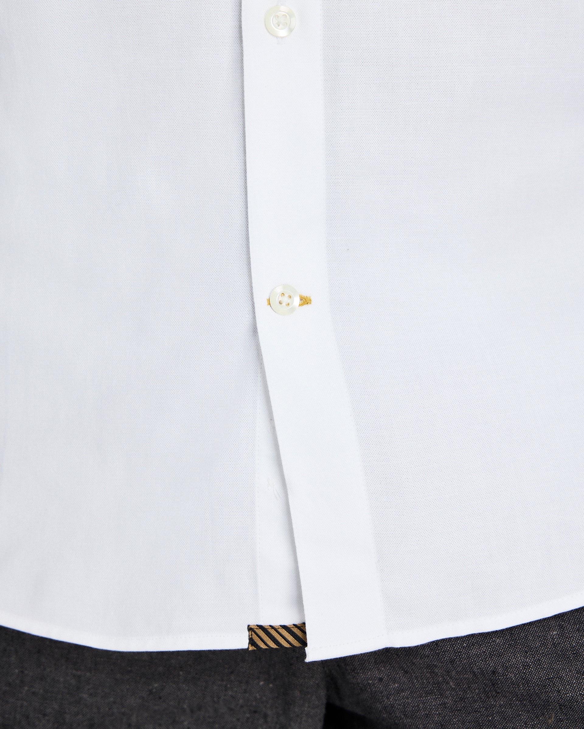 Close-up of a white shirt with a button and cuff detail on a white background