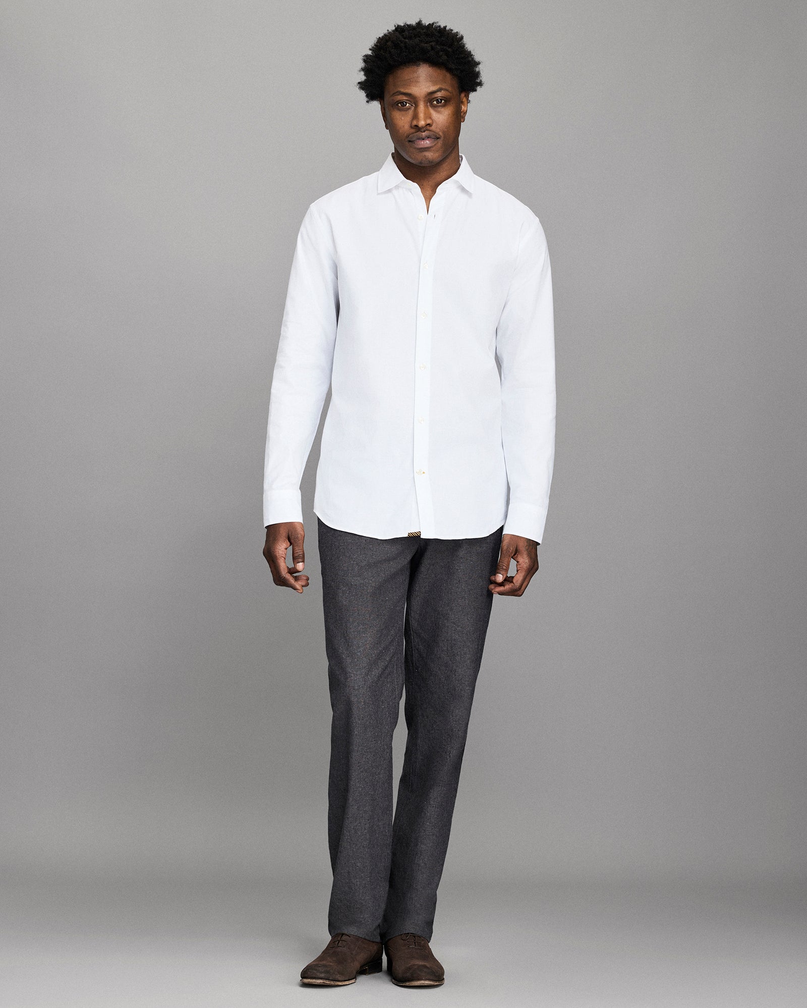 Man wearing a white shirt and gray pants against a gray background