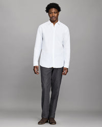 Man wearing a white shirt and gray pants against a gray background