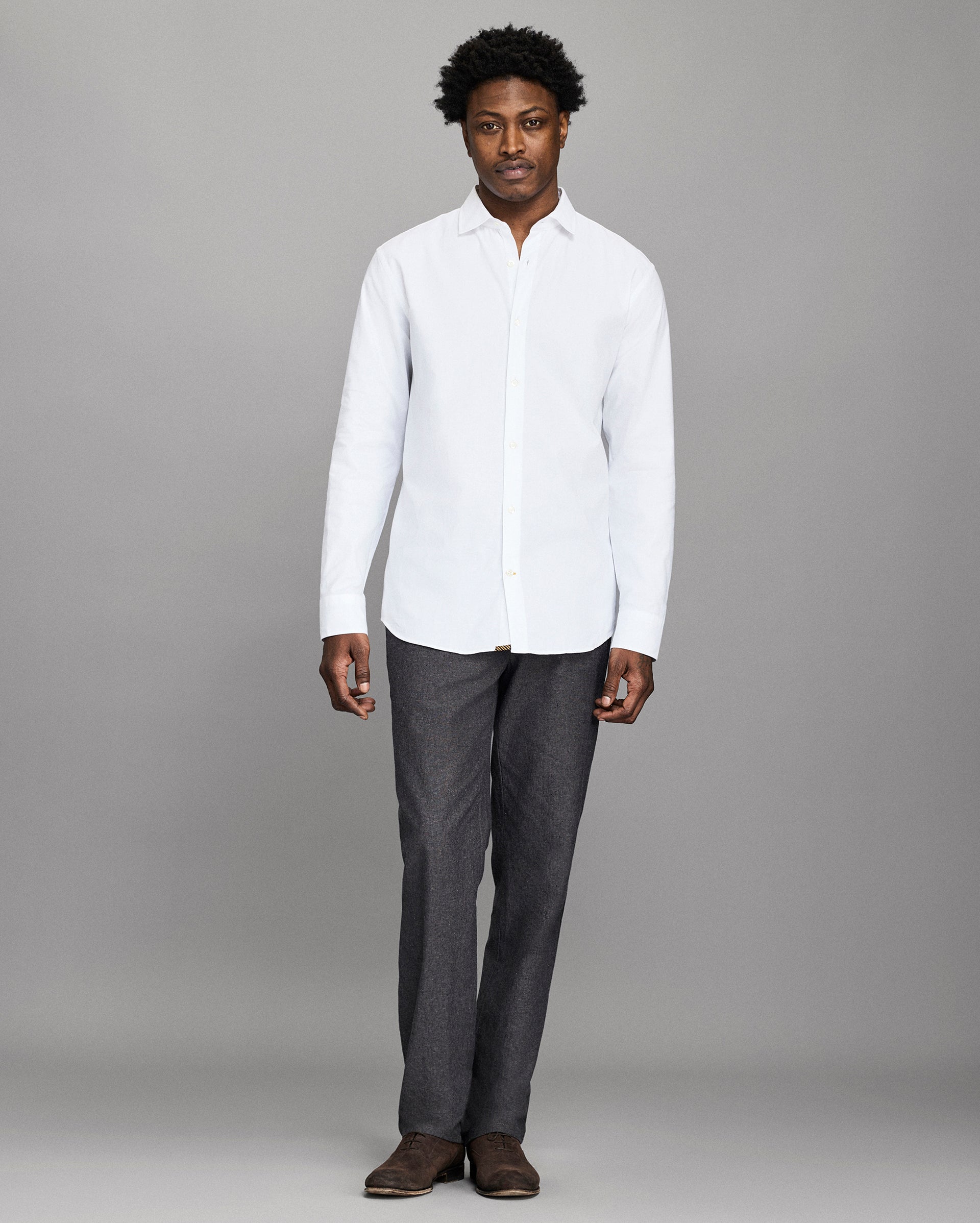 Man wearing a white shirt and gray pants against a gray background