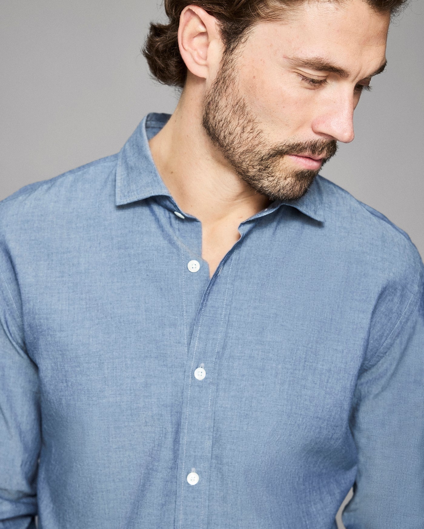 Man wearing a blue shirt against a gray background