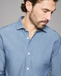 Man wearing a blue shirt against a gray background