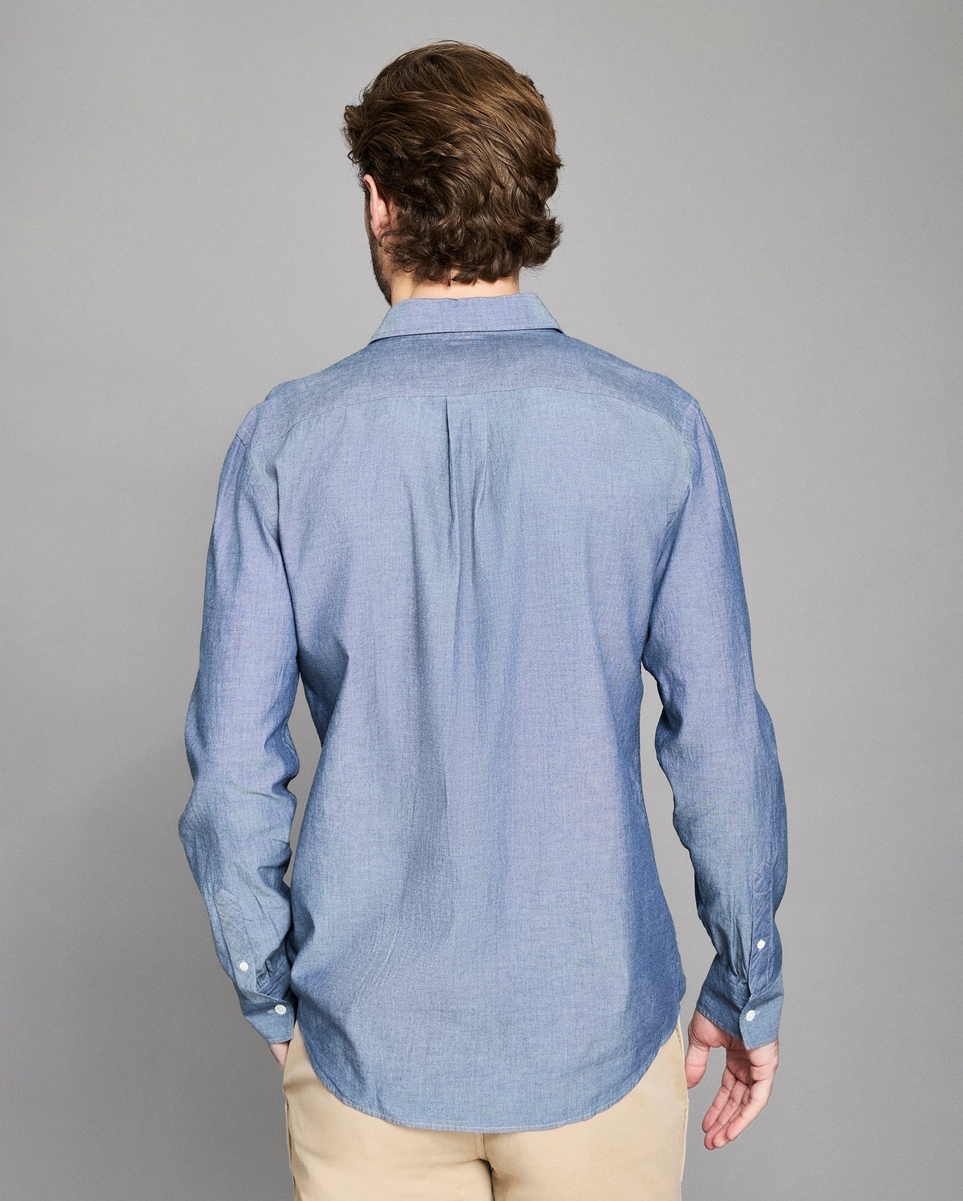 Man wearing a blue shirt from behind on a gray background
