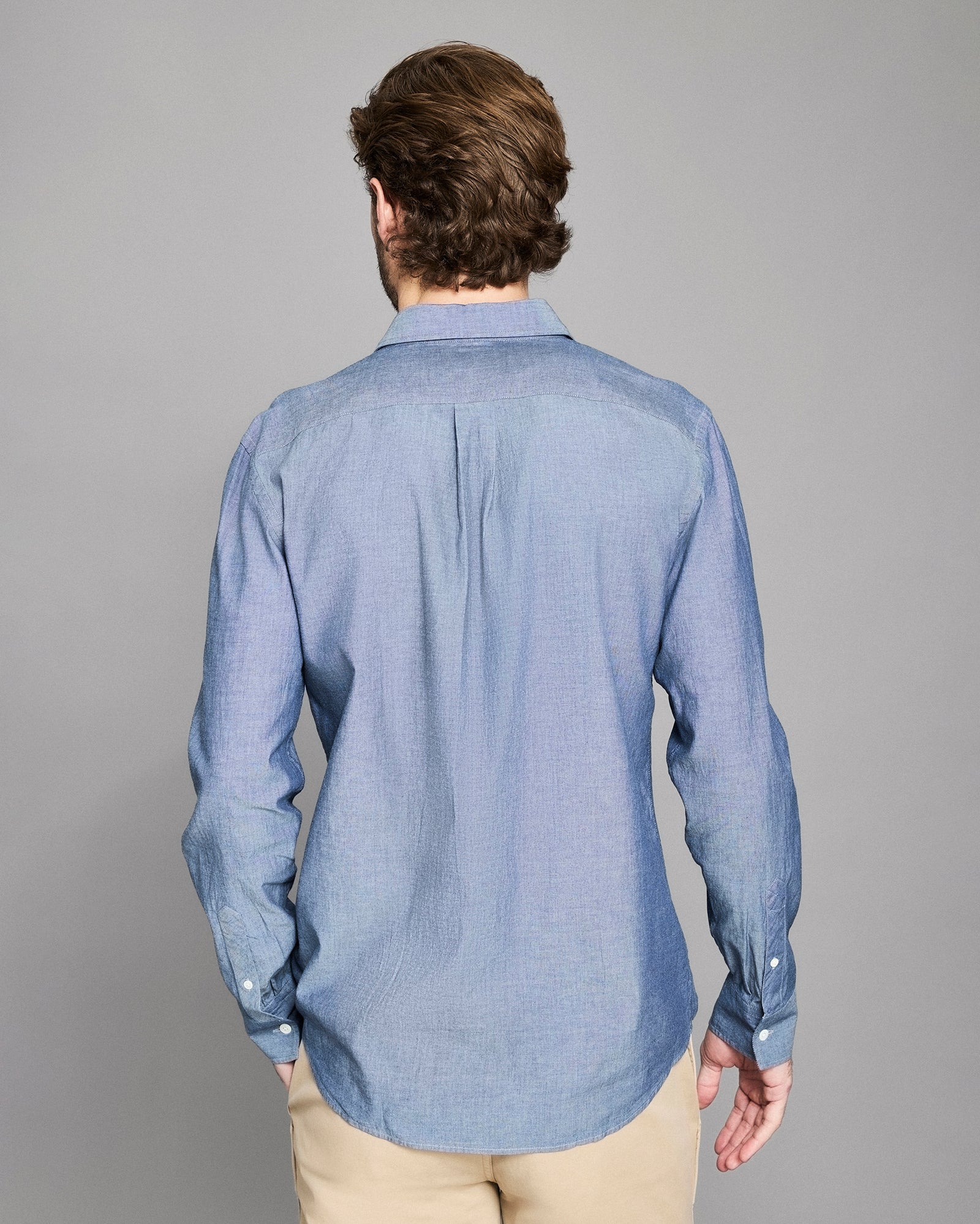 Man wearing a blue shirt from behind on a gray background