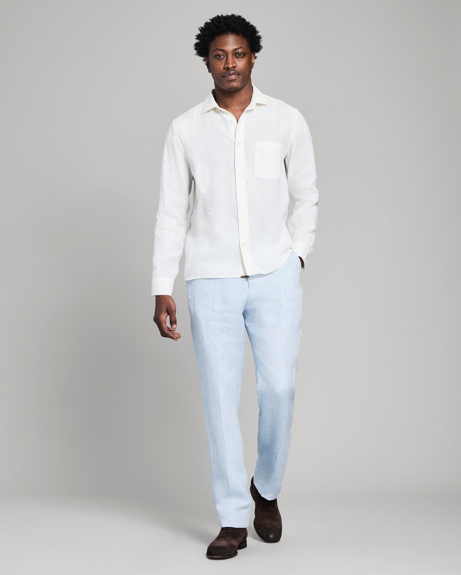 Man wearing a white shirt and light blue jeans on a gray background