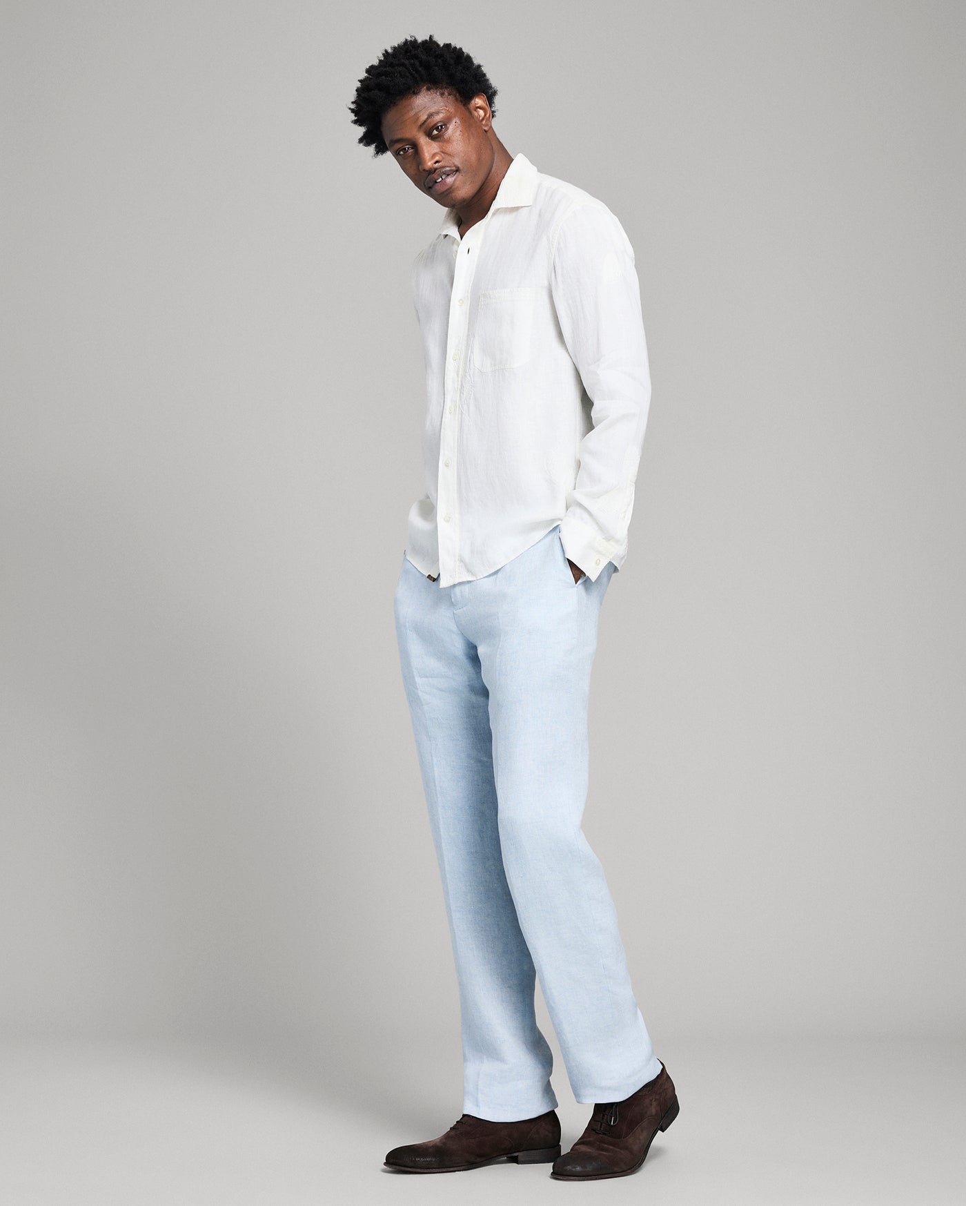Person wearing a white shirt and light blue jeans on a gray background