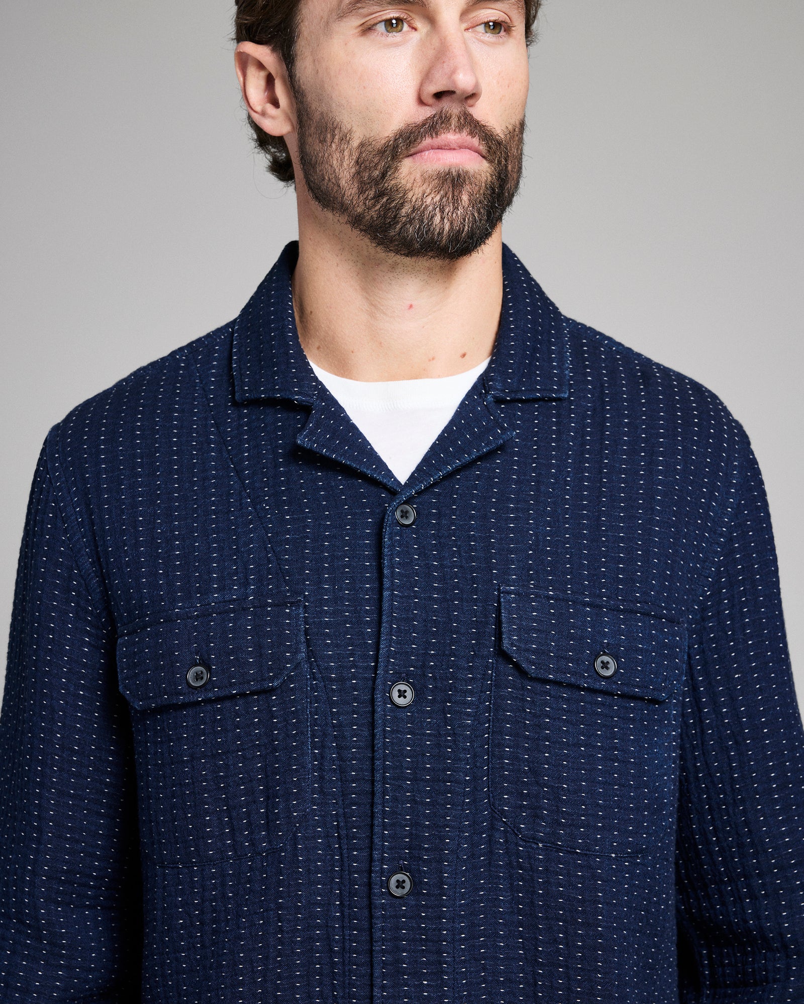 Man wearing a navy blue patterned shirt against a gray background