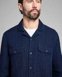 Man wearing a navy blue patterned shirt against a gray background