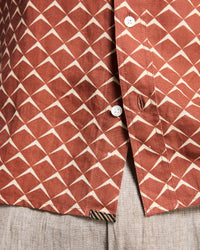 Close-up of a red and white geometric patterned shirt on a textured surface
