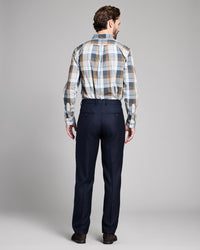 Man wearing a plaid shirt and dark pants on a gray background