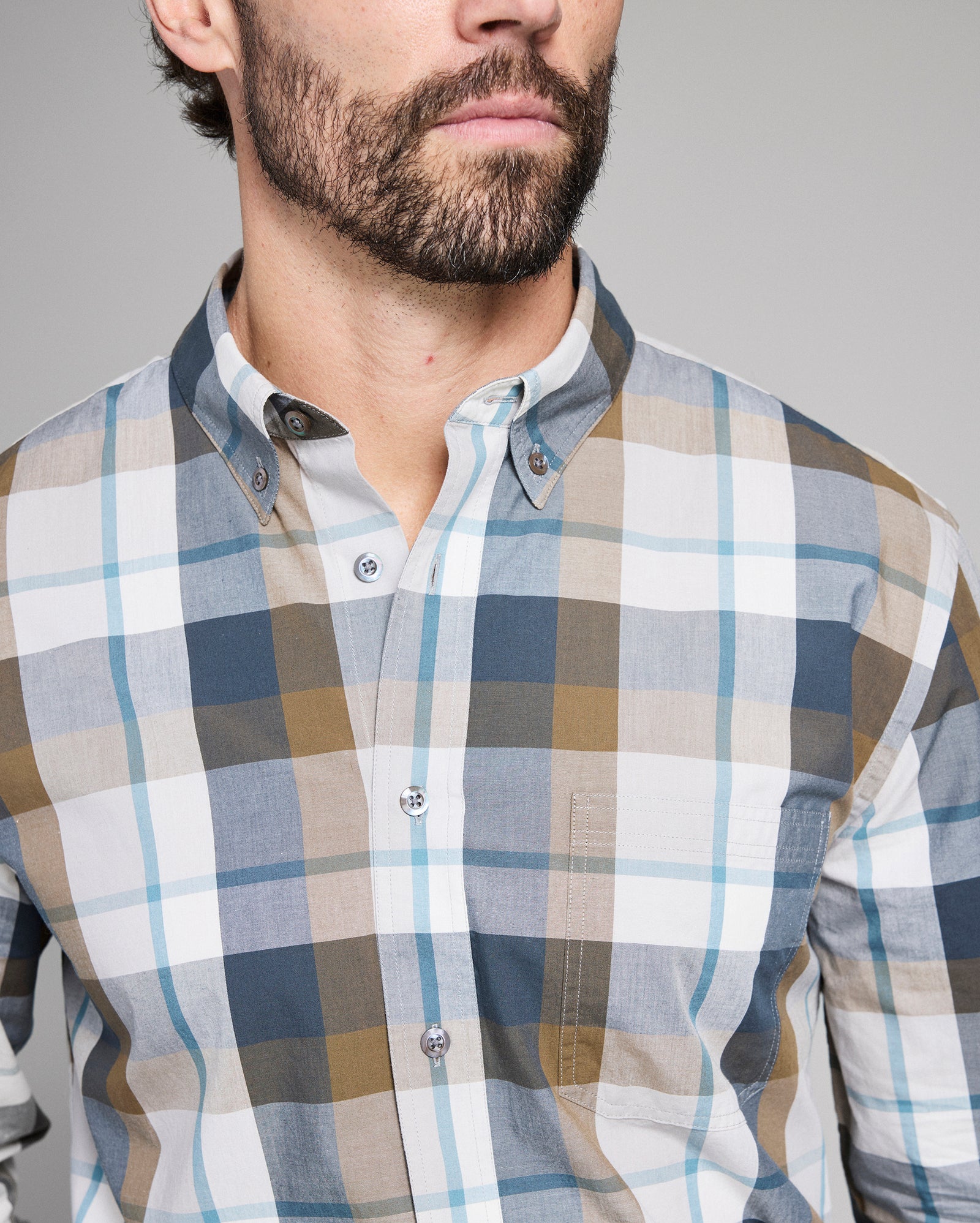 Man wearing a plaid shirt with a neutral background
