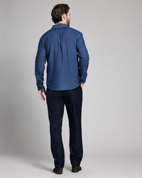 Man wearing a blue shirt and dark pants on a gray background
