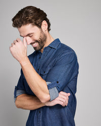 Man wearing a blue denim shirt against a gray background