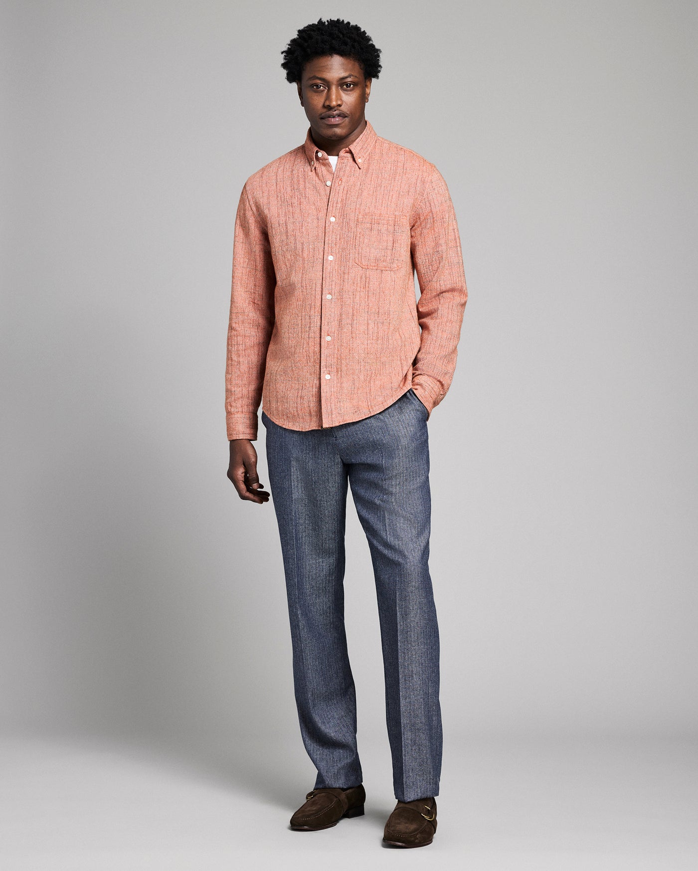 Man wearing a orange checkered shirt and blue jeans on a gray background