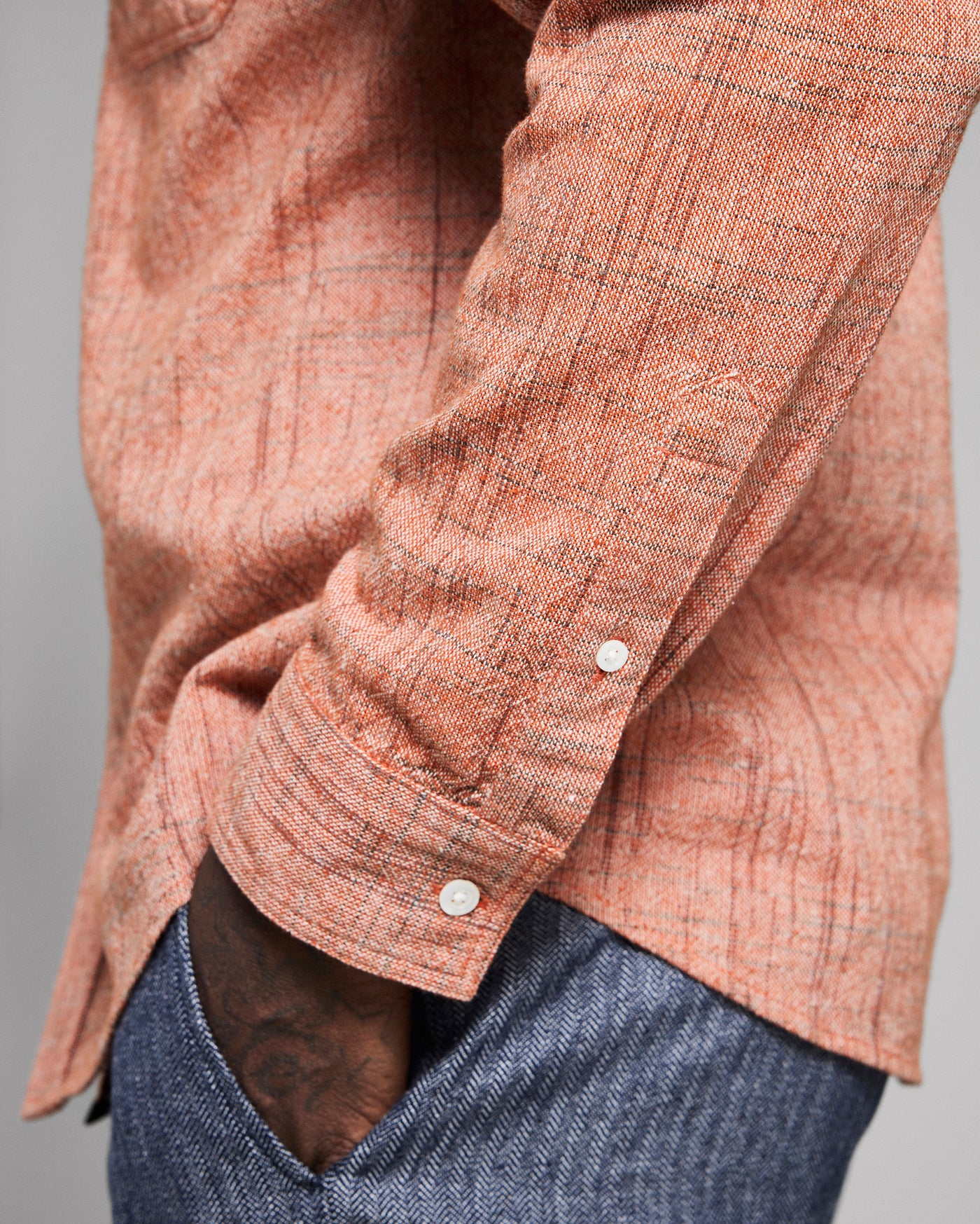 Close-up of a orange textured shirt with rolled-up sleeve on a gray background