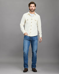 Man wearing a white shirt and blue jeans against a gray background
