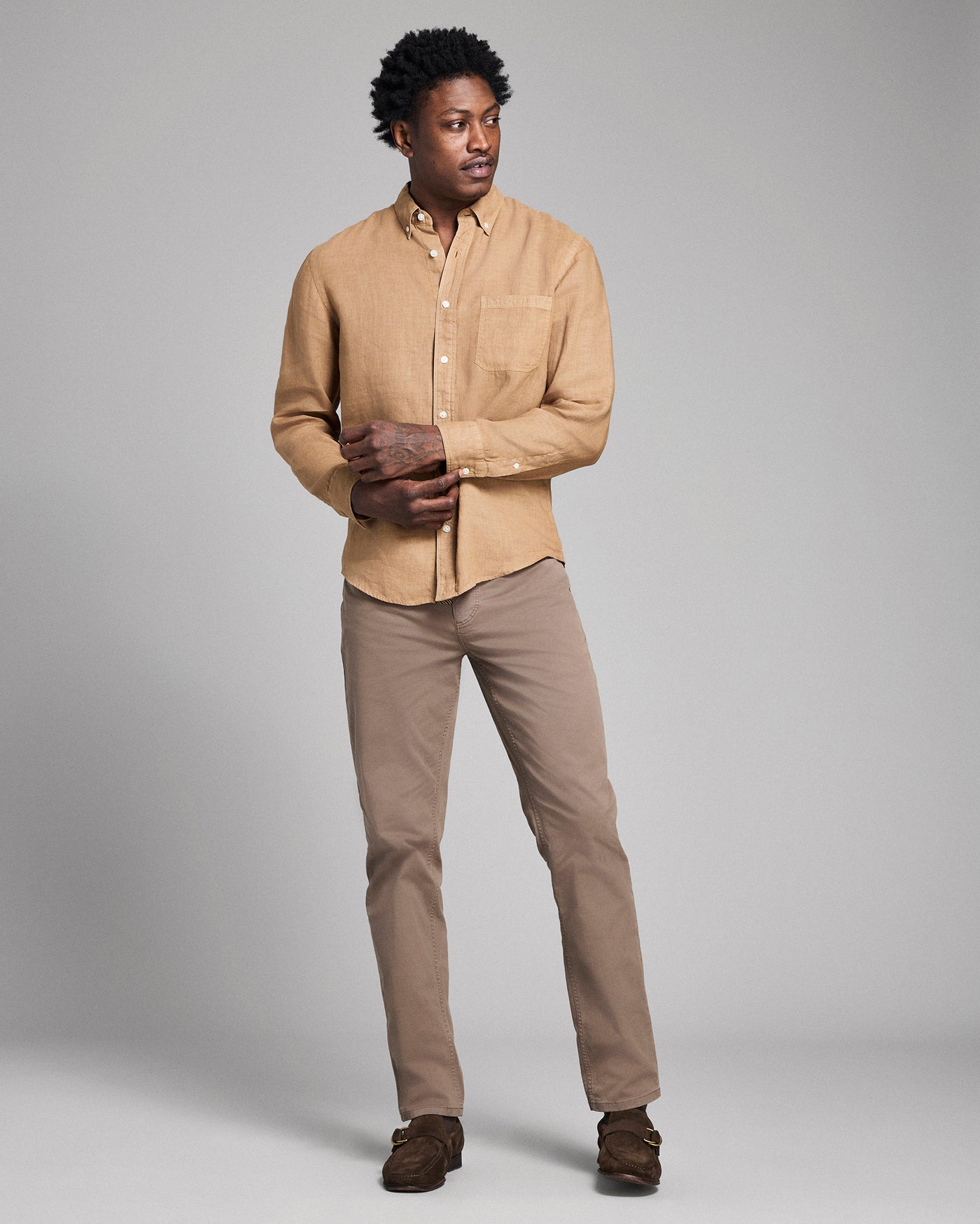 Man wearing a beige shirt and pants with gloves against a gray background