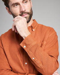 Man wearing an orange shirt with a neutral background