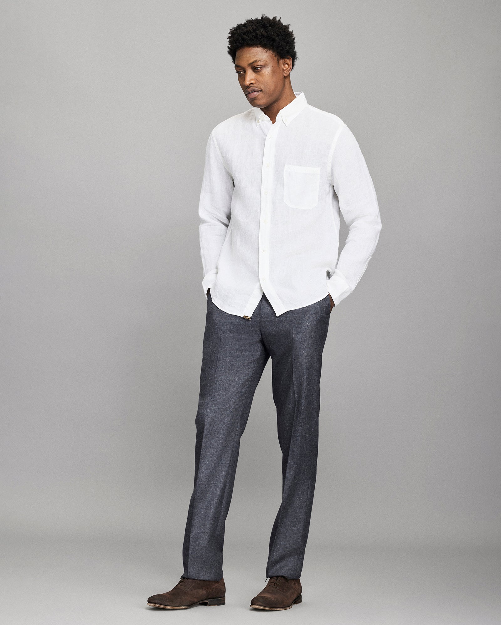 Man wearing a white shirt and gray pants against a gray background