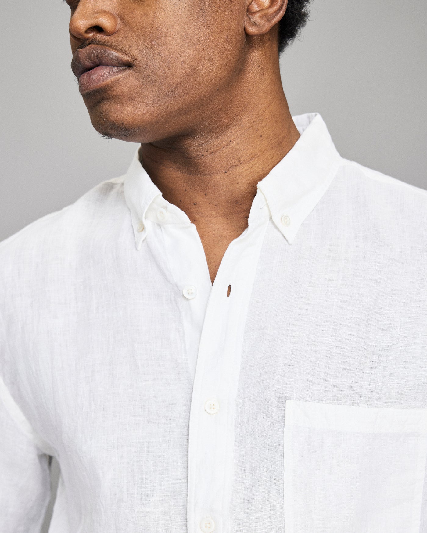 Man wearing a white button-up shirt against a gray background