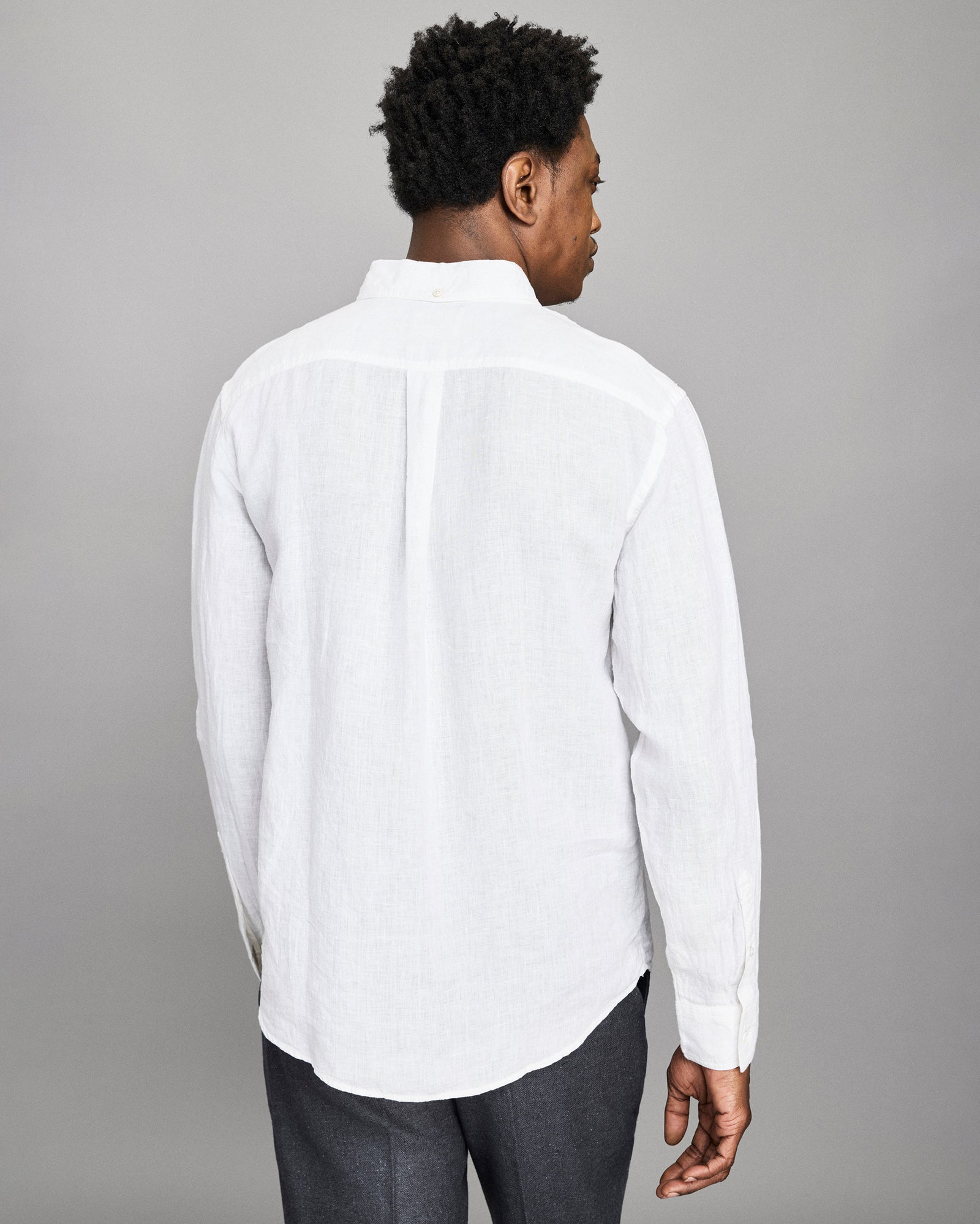 Man wearing a white button-up shirt against a gray background
