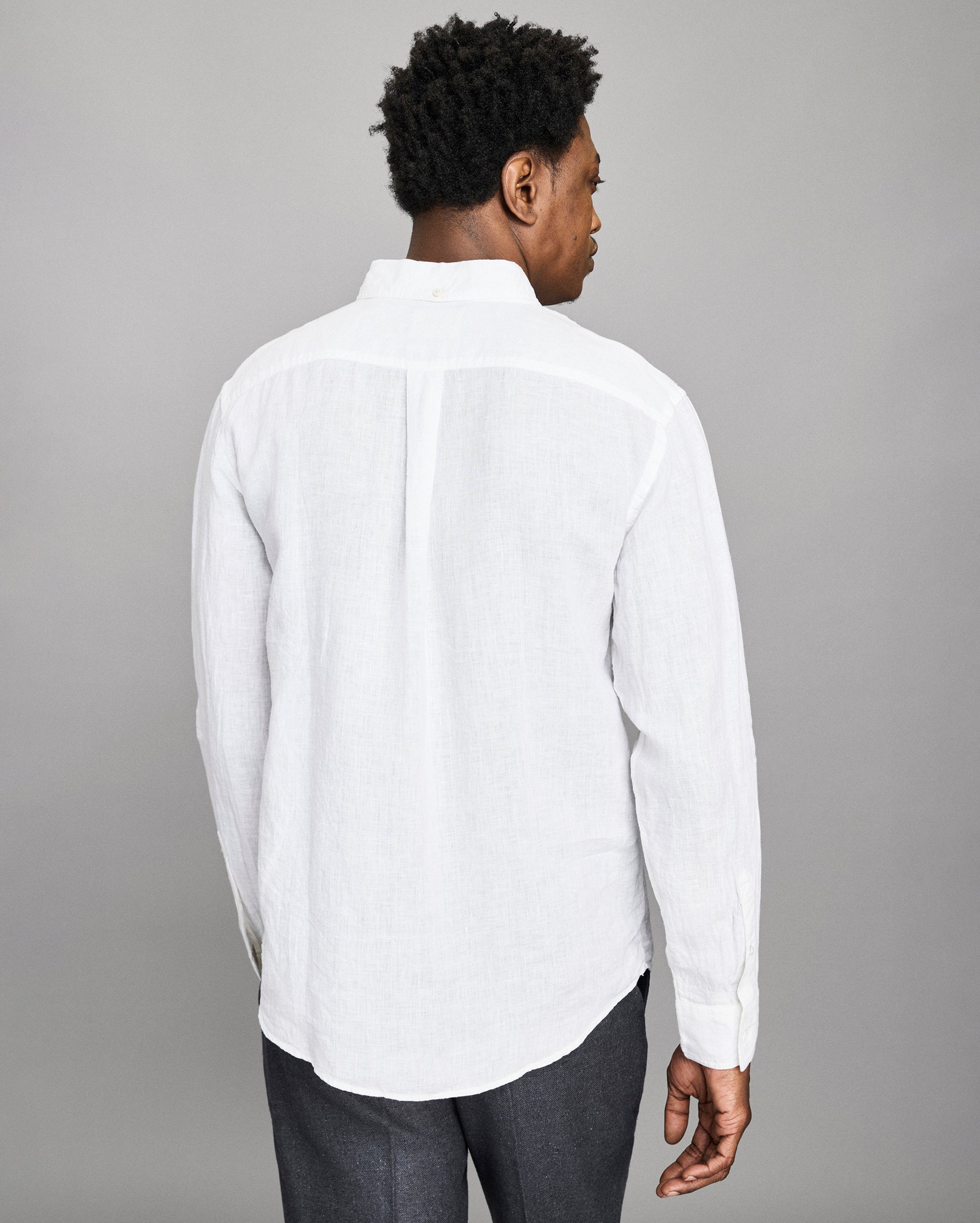 Man wearing a white button-up shirt against a gray background